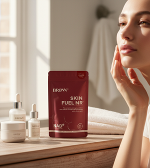 BRONN Skin Fuel NR supplement package on a wooden surface with a woman touching her face.