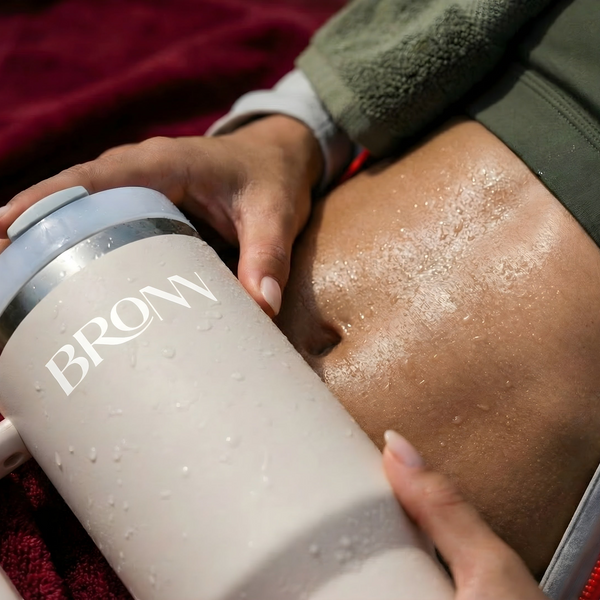 Person holding a BRONN branded tumbler with a red blanket in the background